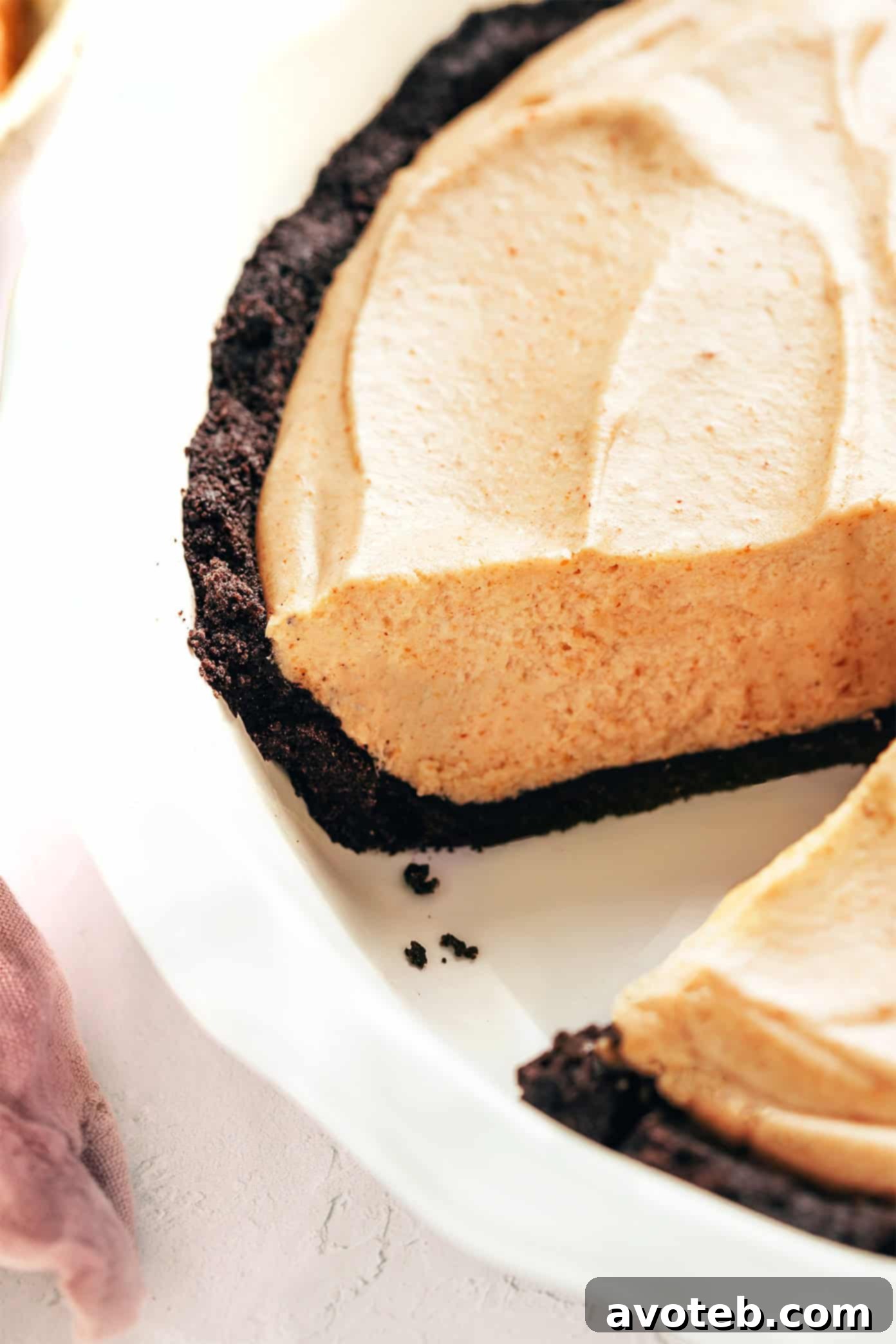 Decadent Peanut Butter Dream Pie 8 A large no-bake peanut butter pie, with one delectable slice already removed, showcasing the thick, creamy filling and the contrasting texture of the rich Oreo cookie crust.