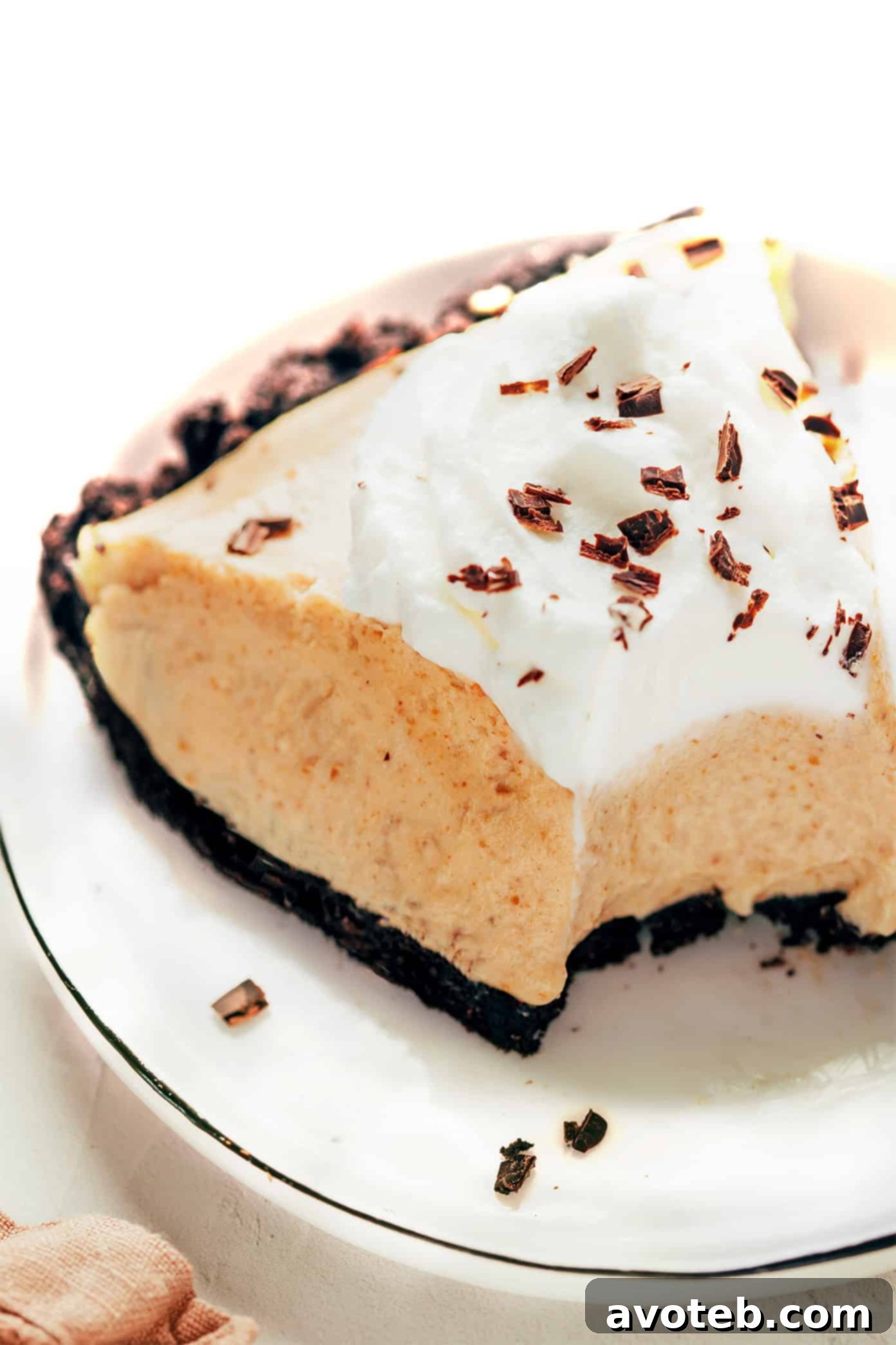 Decadent Peanut Butter Dream Pie 6 A delectable slice of no-bake peanut butter pie with an Oreo crust, garnished generously with fresh whipped cream and a sprinkle of chocolate shavings, illustrating its perfect, fluffy texture.