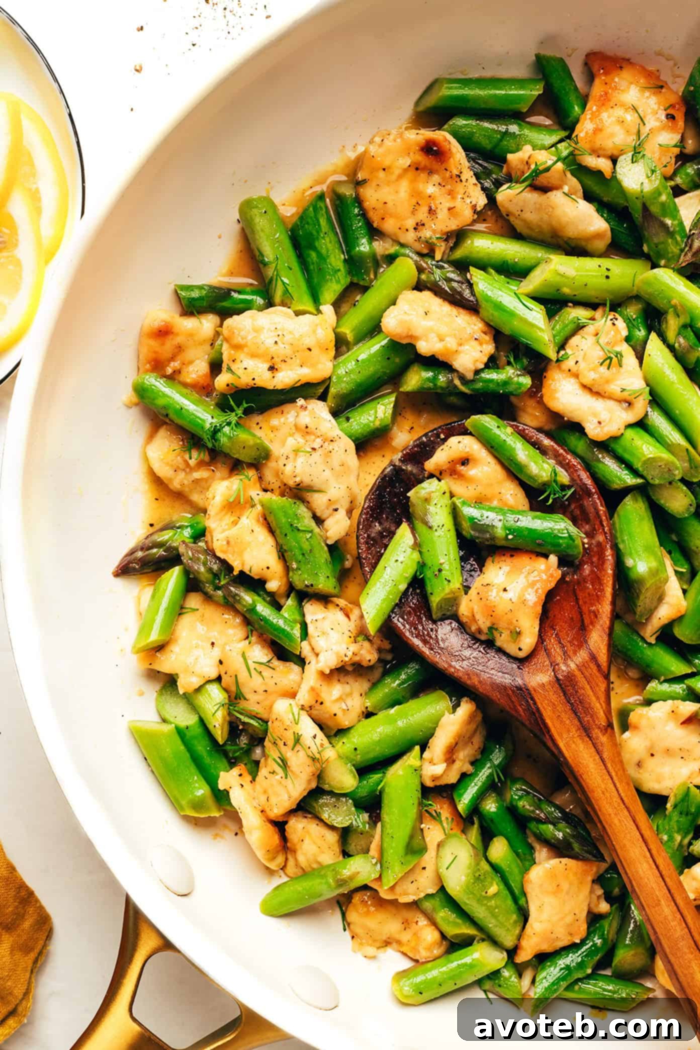 Serving of lemon pepper chicken and asparagus stir-fry in a bowl, garnished with fresh herbs.