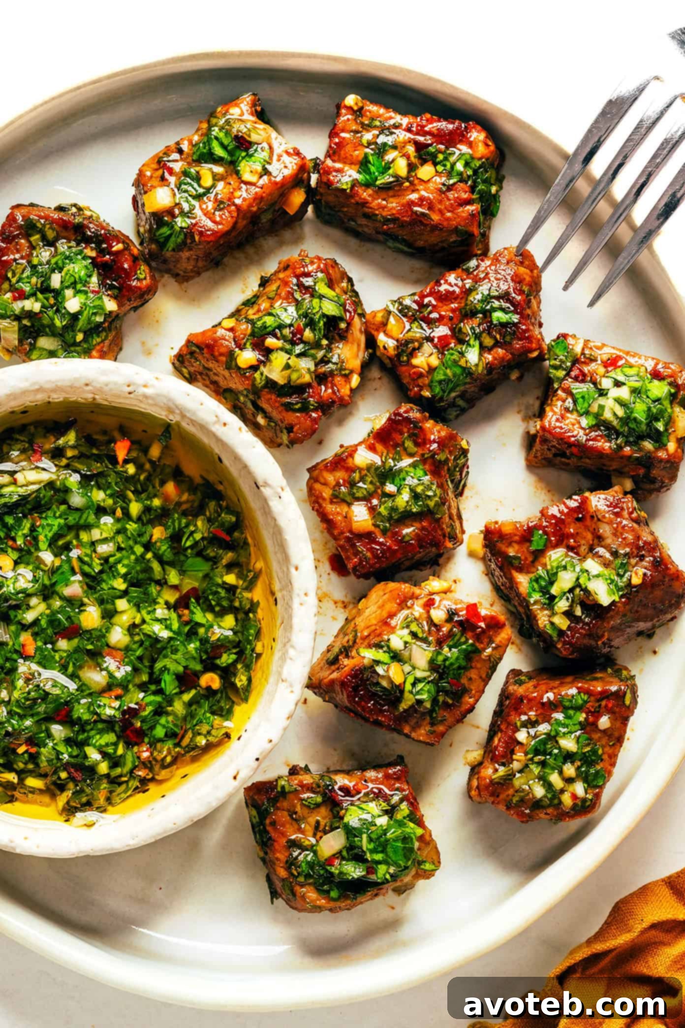 Plated chimichurri steak bites with lemon wedge