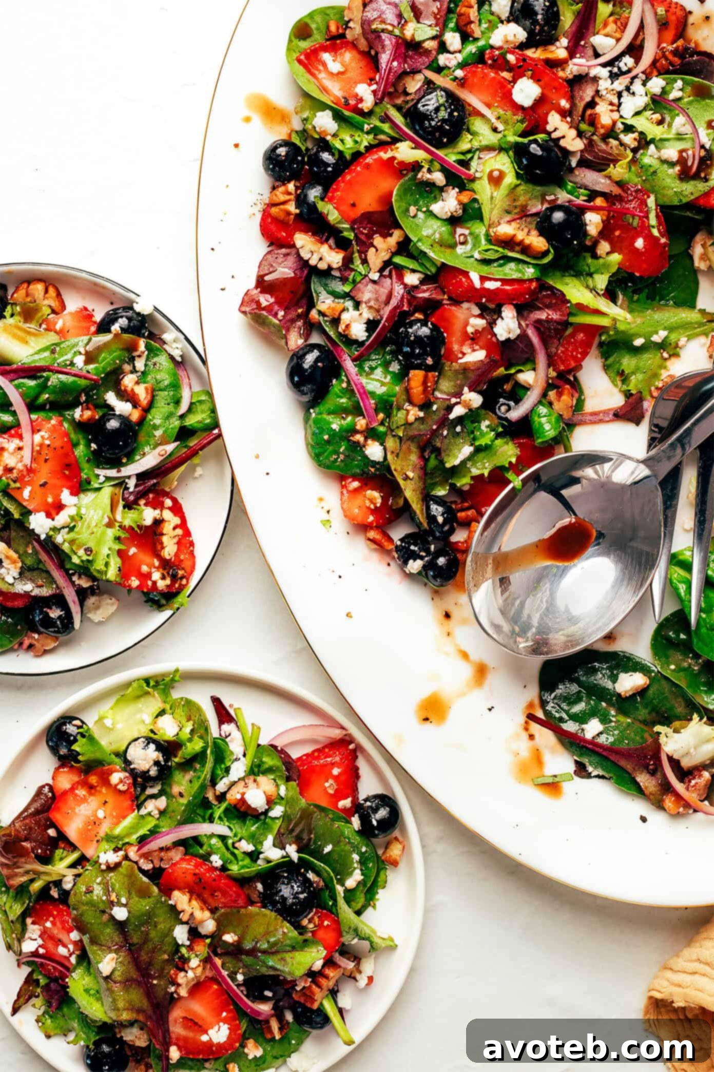 A beautifully presented balsamic berry spinach salad, overflowing with fresh strawberries, blueberries, and spinach.
