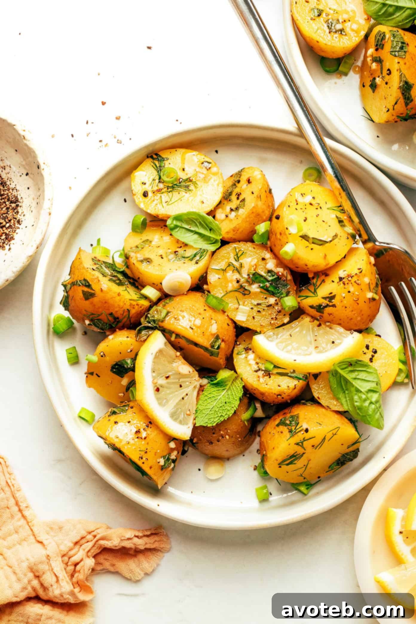 A flat lay of ingredients for the lemon herb potato salad, including whole and sliced lemons, fresh herbs like dill and basil, and small golden potatoes.