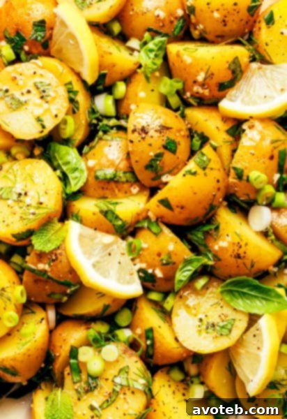 Lemon Herb Potato Salad ready to serve, garnished with fresh herbs in a white bowl.