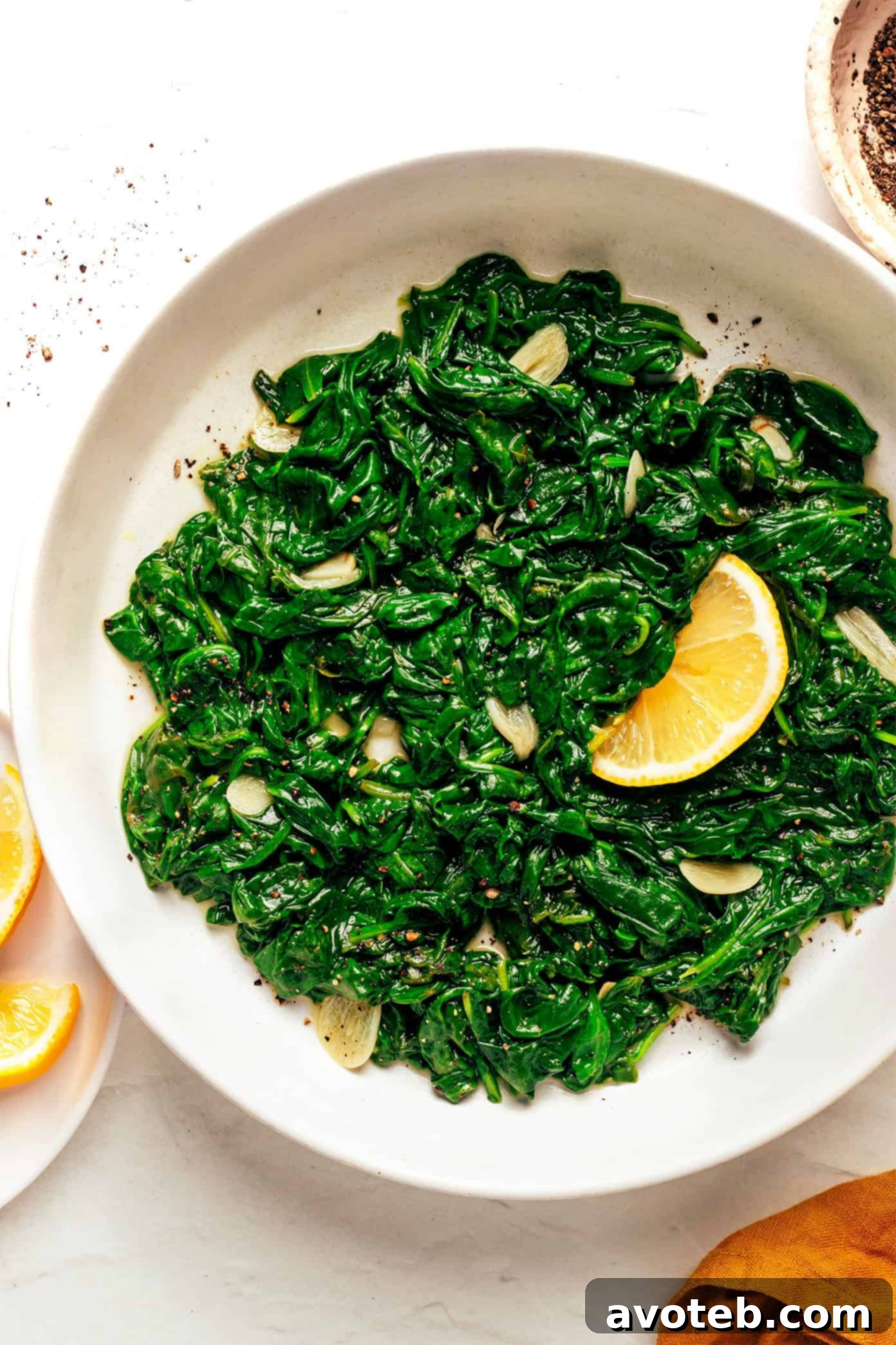 A bowl of sautéed spinach garnished with lemon