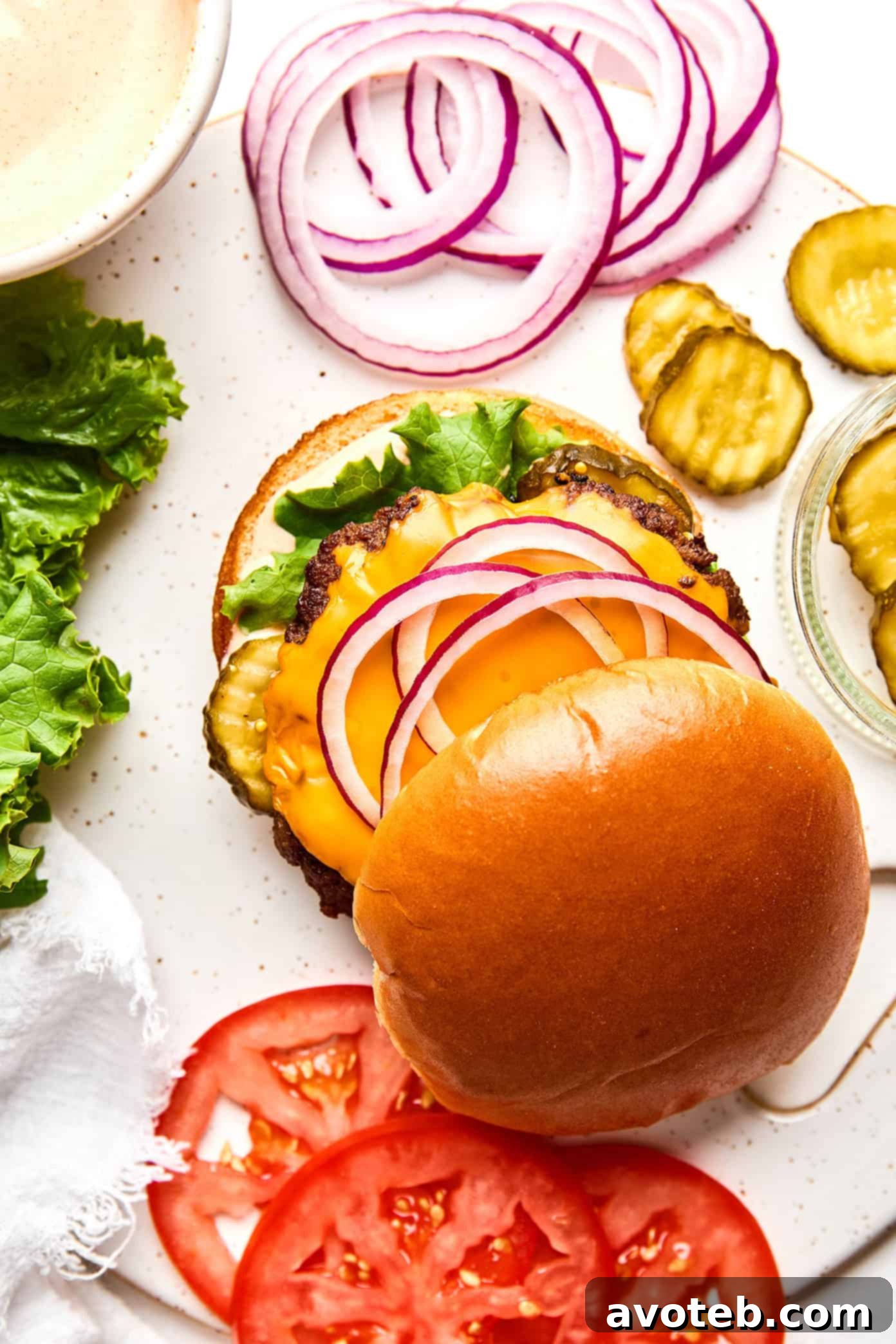 A beautifully assembled smash burger with all the toppings, including fresh lettuce, tomato, onion, and a special sauce.