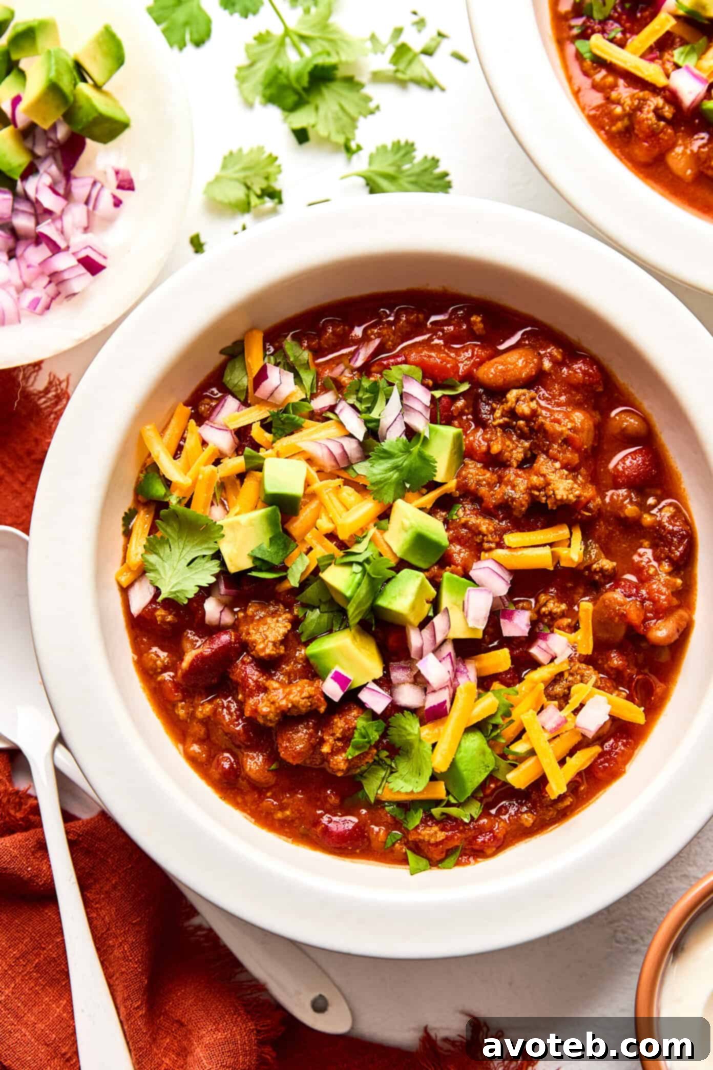 A steaming bowl of 5-ingredient chili garnished with sour cream and fresh cilantro, ready to be enjoyed.