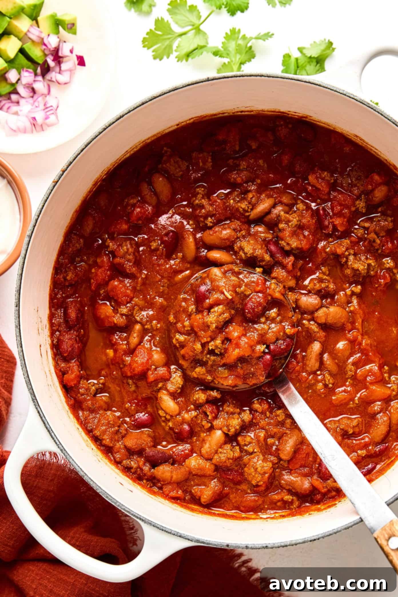 A close-up of the chili simmering in a large pot, showing the rich texture and vibrant colors of the ingredients.