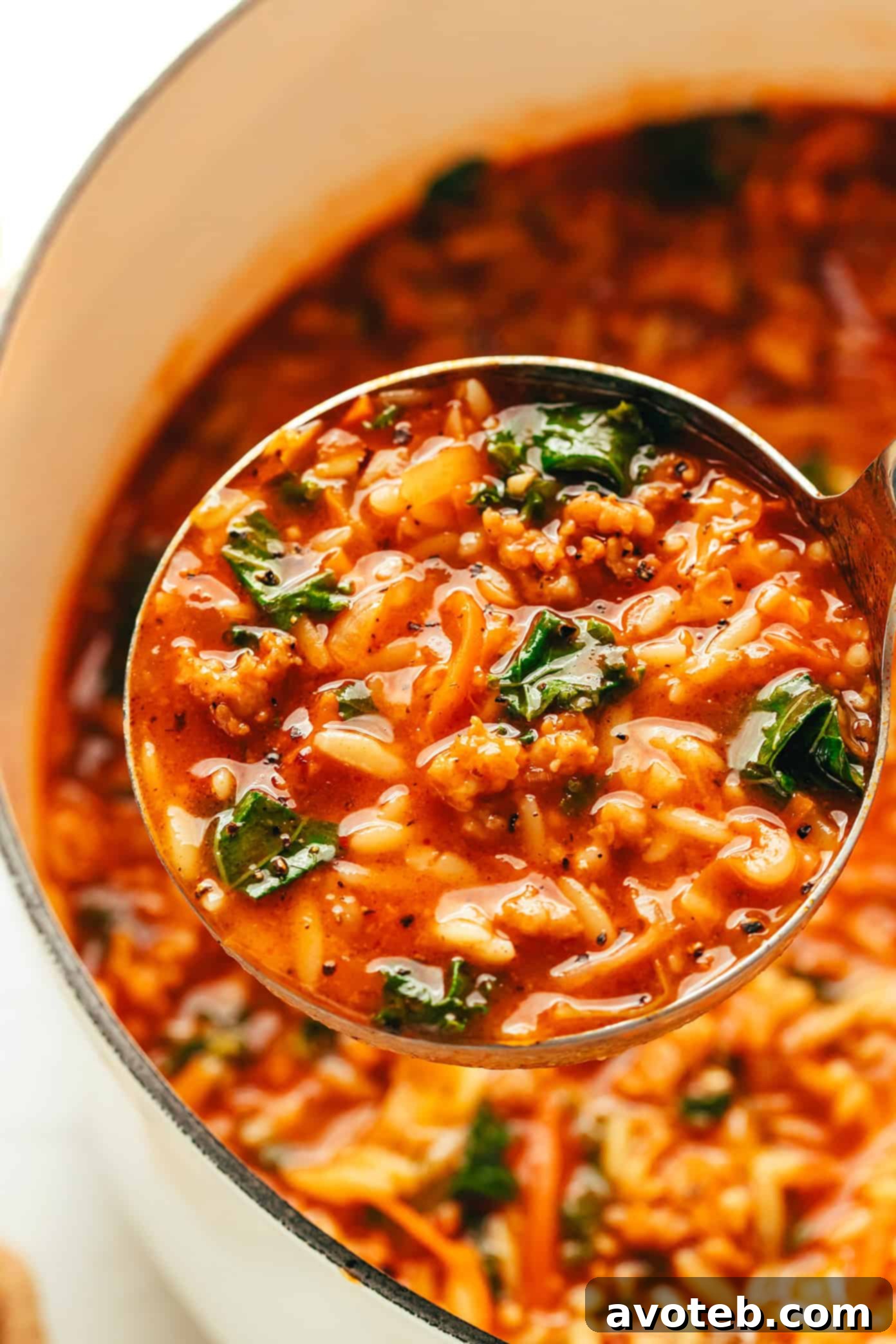 An overhead shot of a bowl of Cabbage Sausage Orzo Soup with a spoon, showing the steam rising.