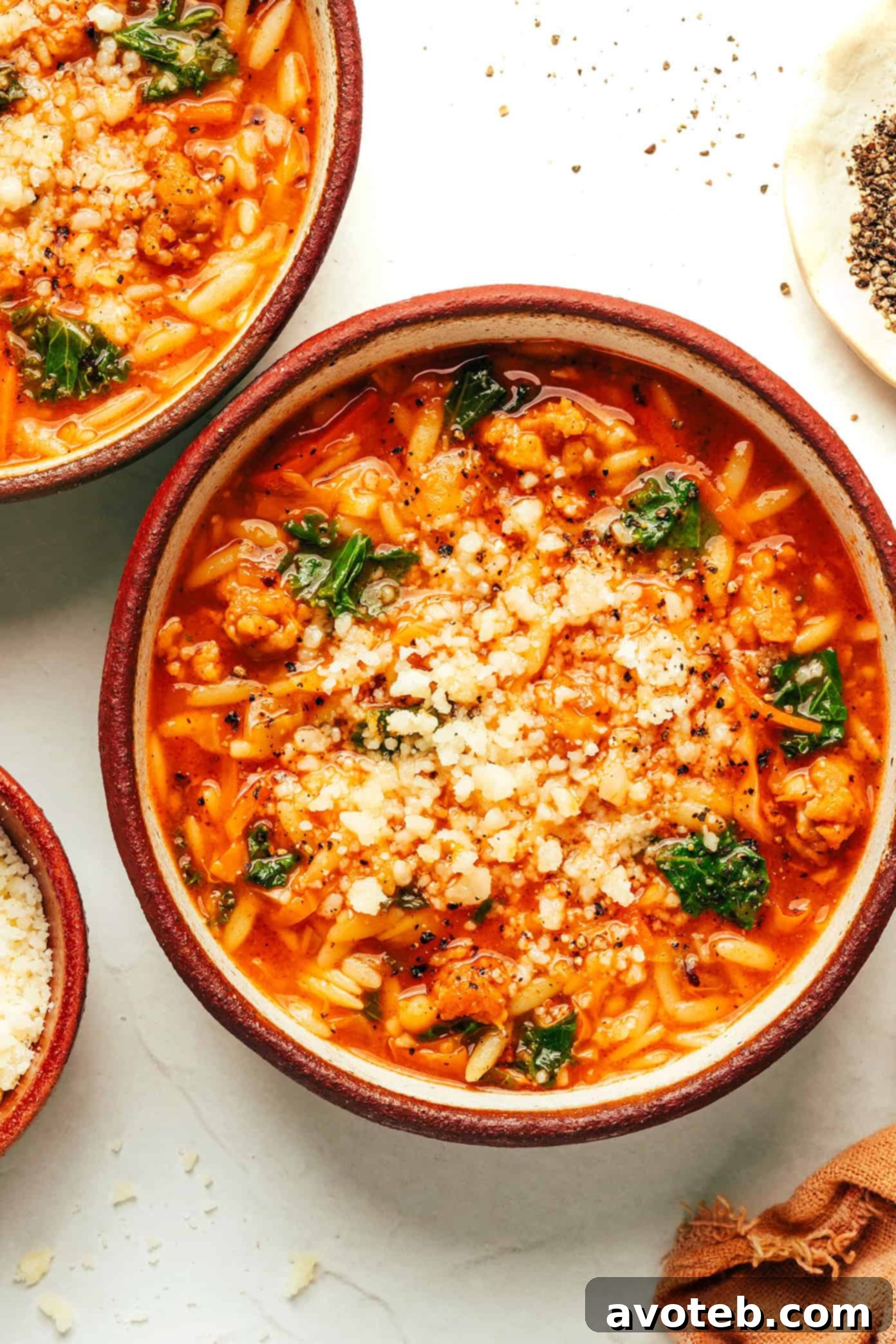 A serving of Cabbage Sausage Orzo Soup in a rustic ceramic bowl with a spoon.