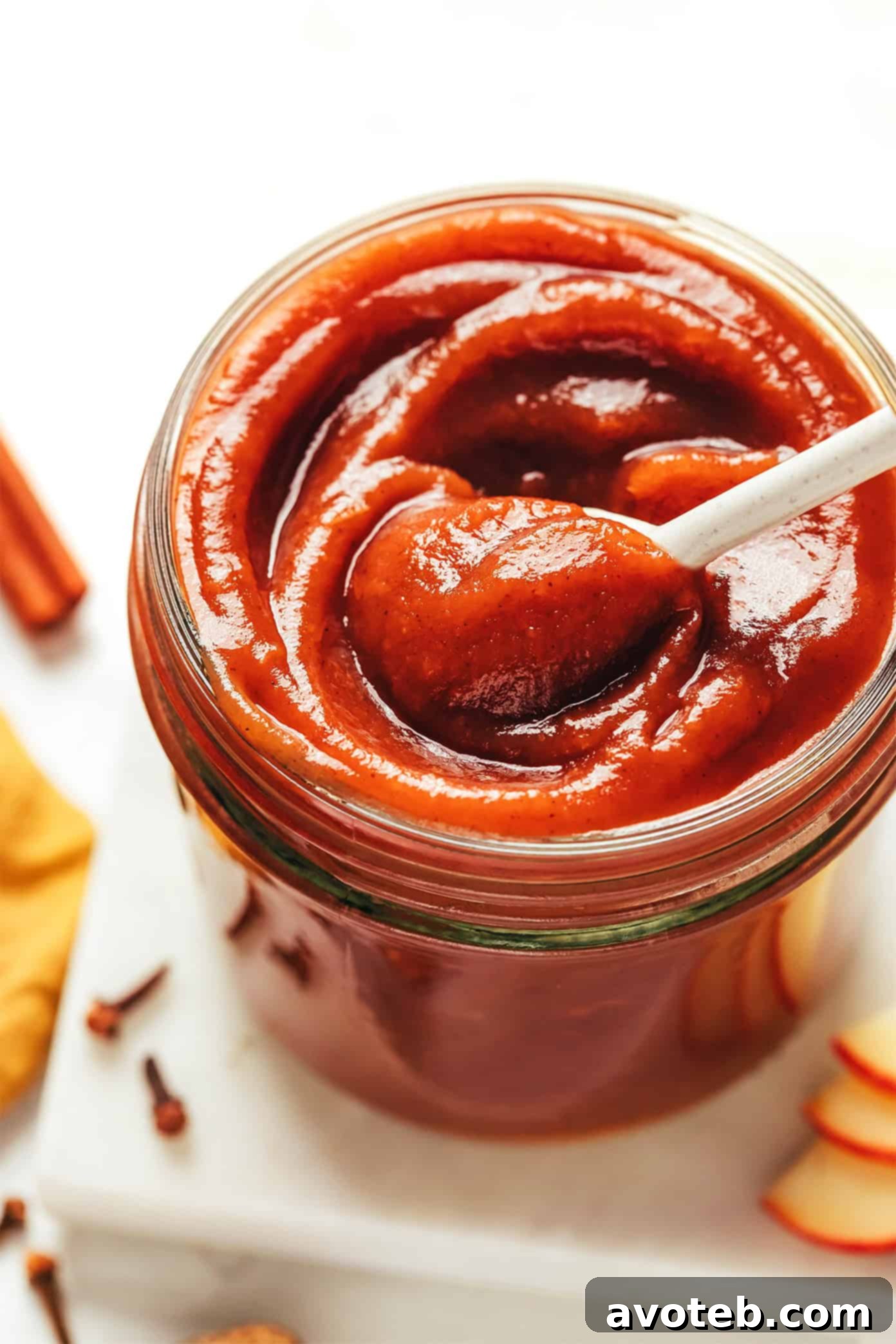 A jar of apple butter on a wooden table with autumn decorations.