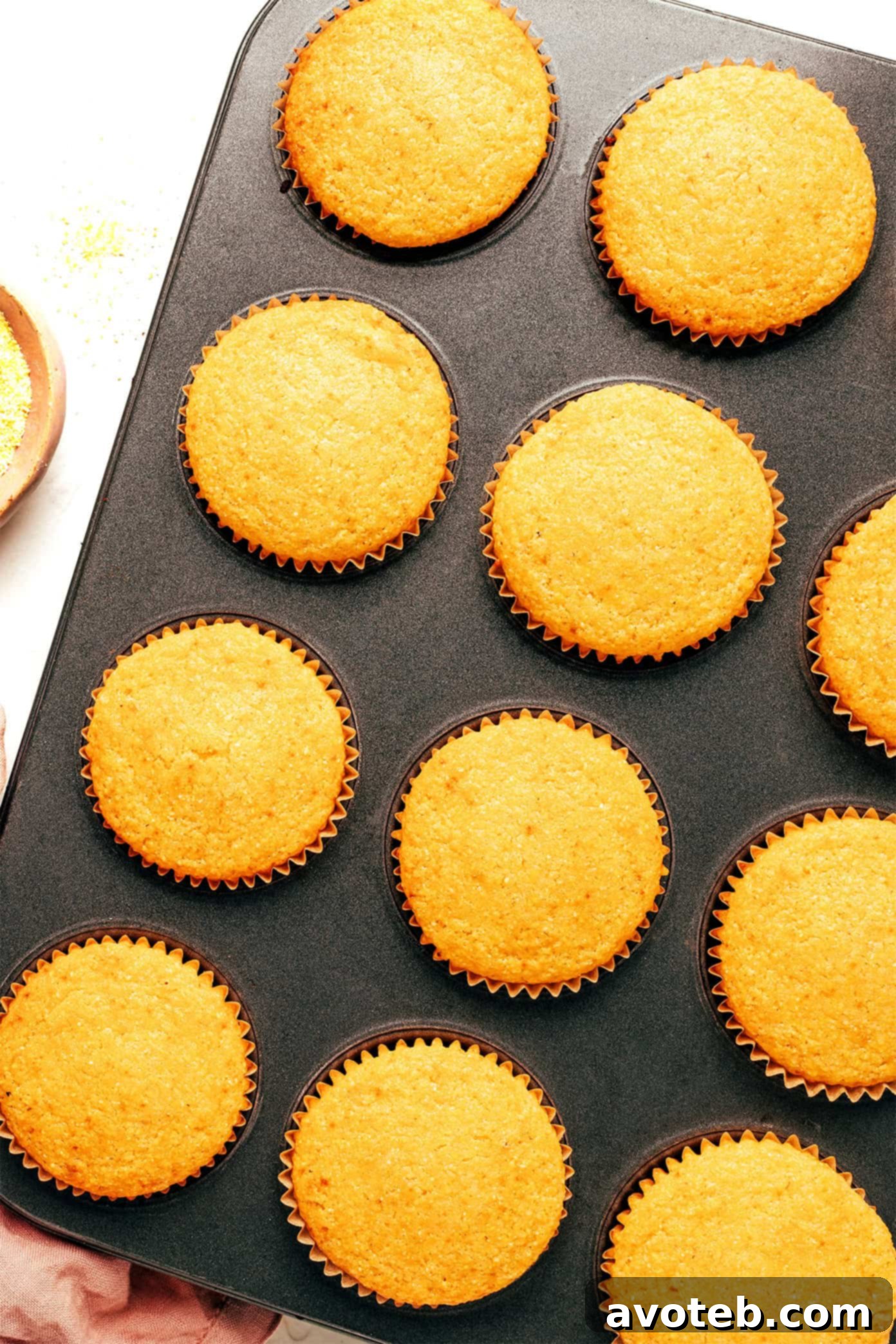 Freshly baked cornbread muffins cooling in a muffin pan