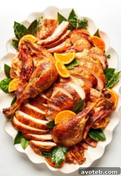 Beautifully carved roast turkey on a platter with oranges and herbs, ready for a holiday dinner.