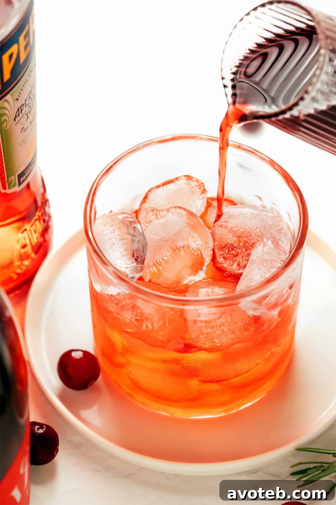 A festive Cranberry Aperol Spritz with a cozy holiday background, adorned with pinecones and ornaments.