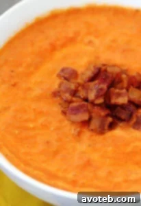 A bowl of creamy Roasted Tomato Bacon Soup with a vibrant red hue.