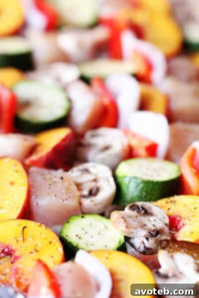 Close-up of ungrilled peach and chicken kabobs on a baking sheet, ready for the grill.