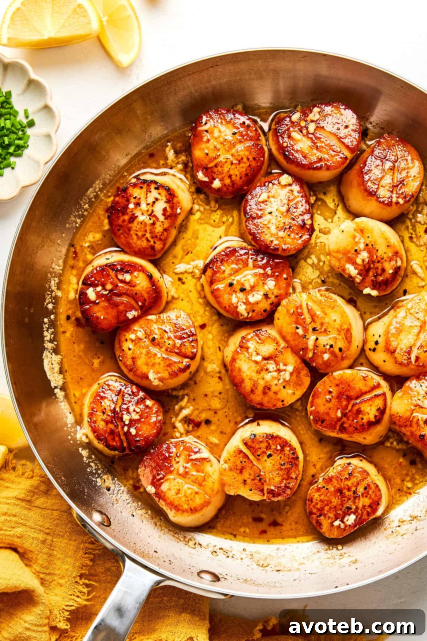 Lemon-Kissed Scallops with Garlic Butter Glaze 6 Seared scallops in a skillet with lemon garlic butter sauce.