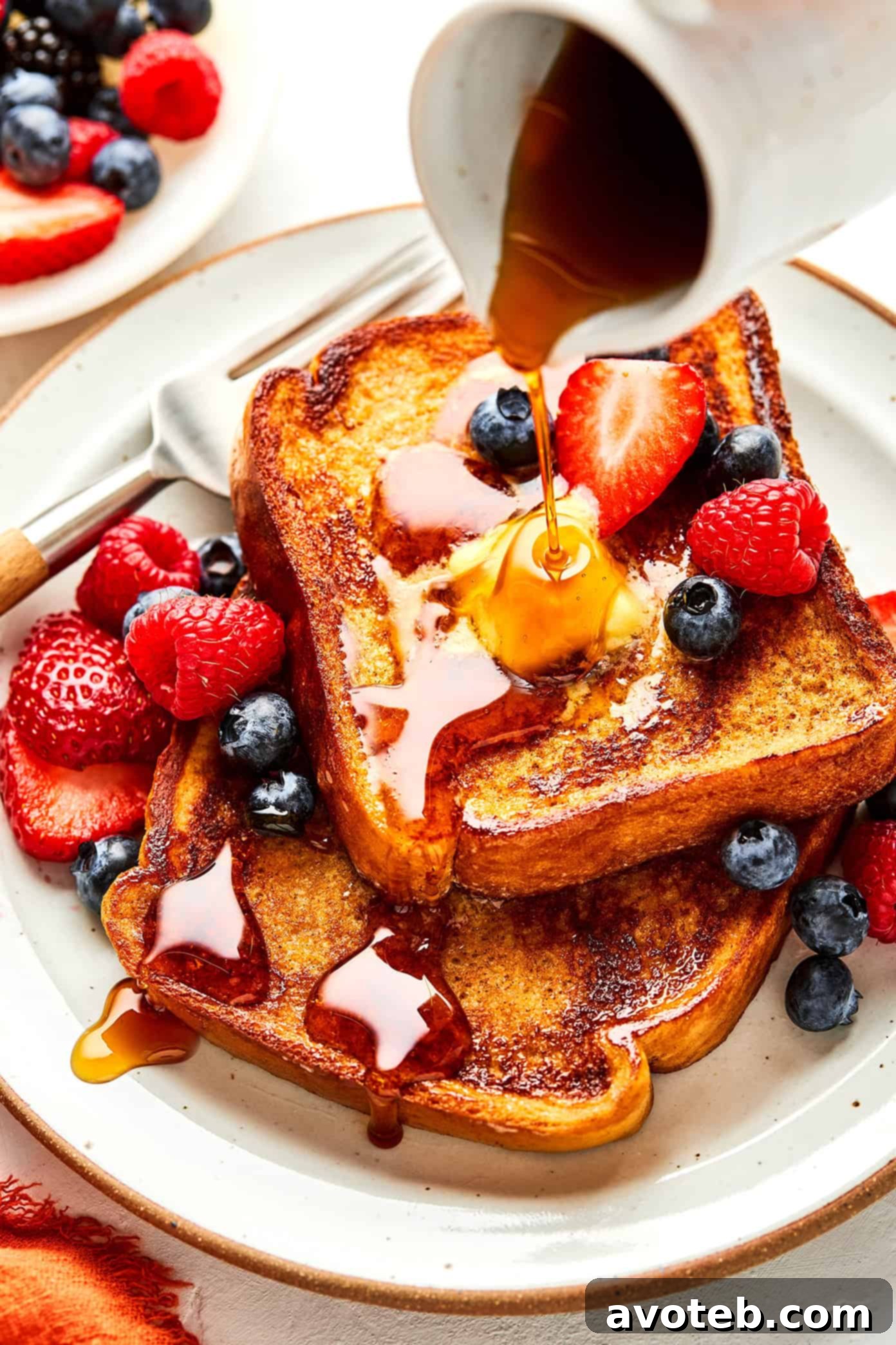 Plated French toast with diverse toppings including berries and syrup