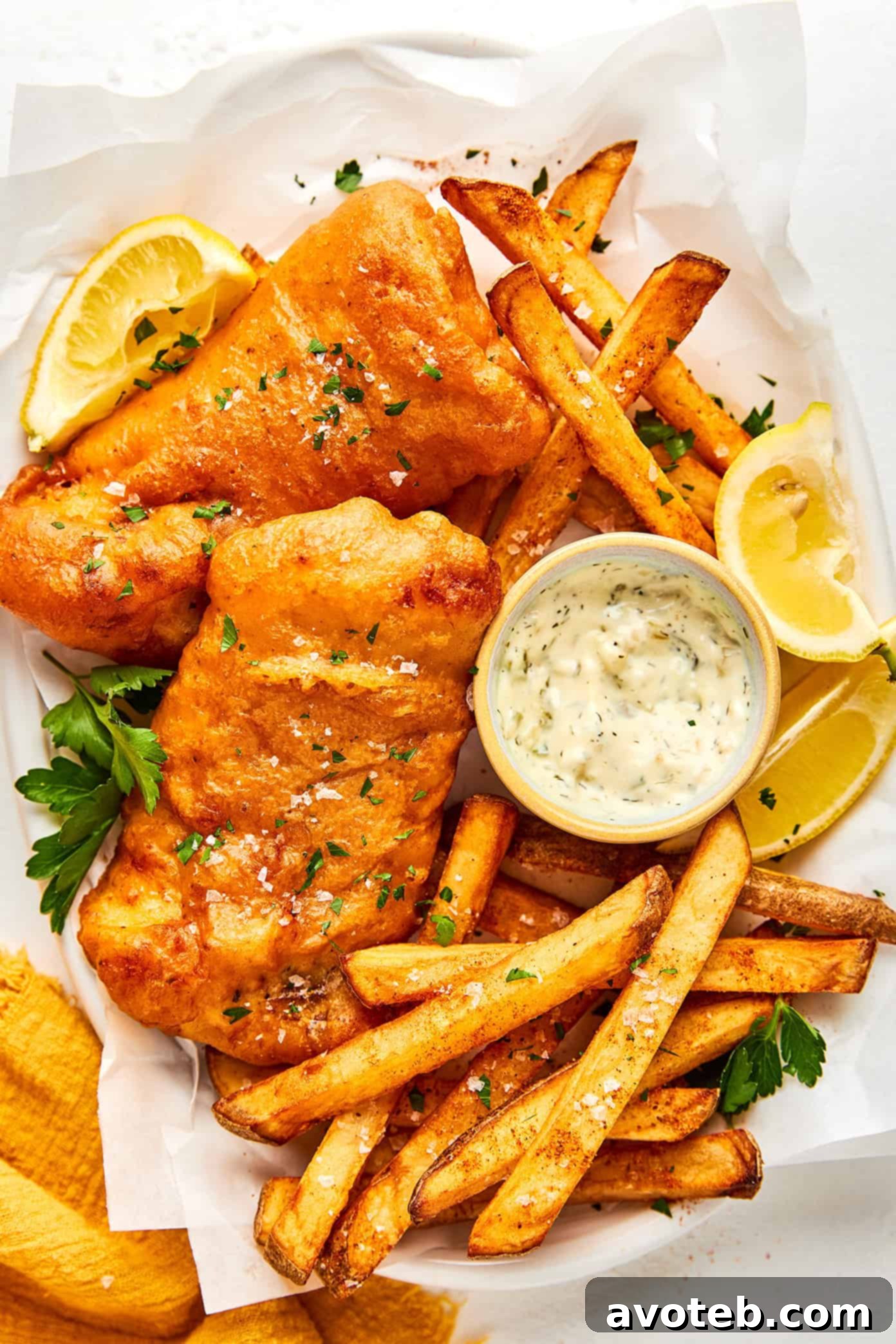Golden brown Old Bay Fish and Chips served with lemon wedges, tartar sauce, and malt vinegar.