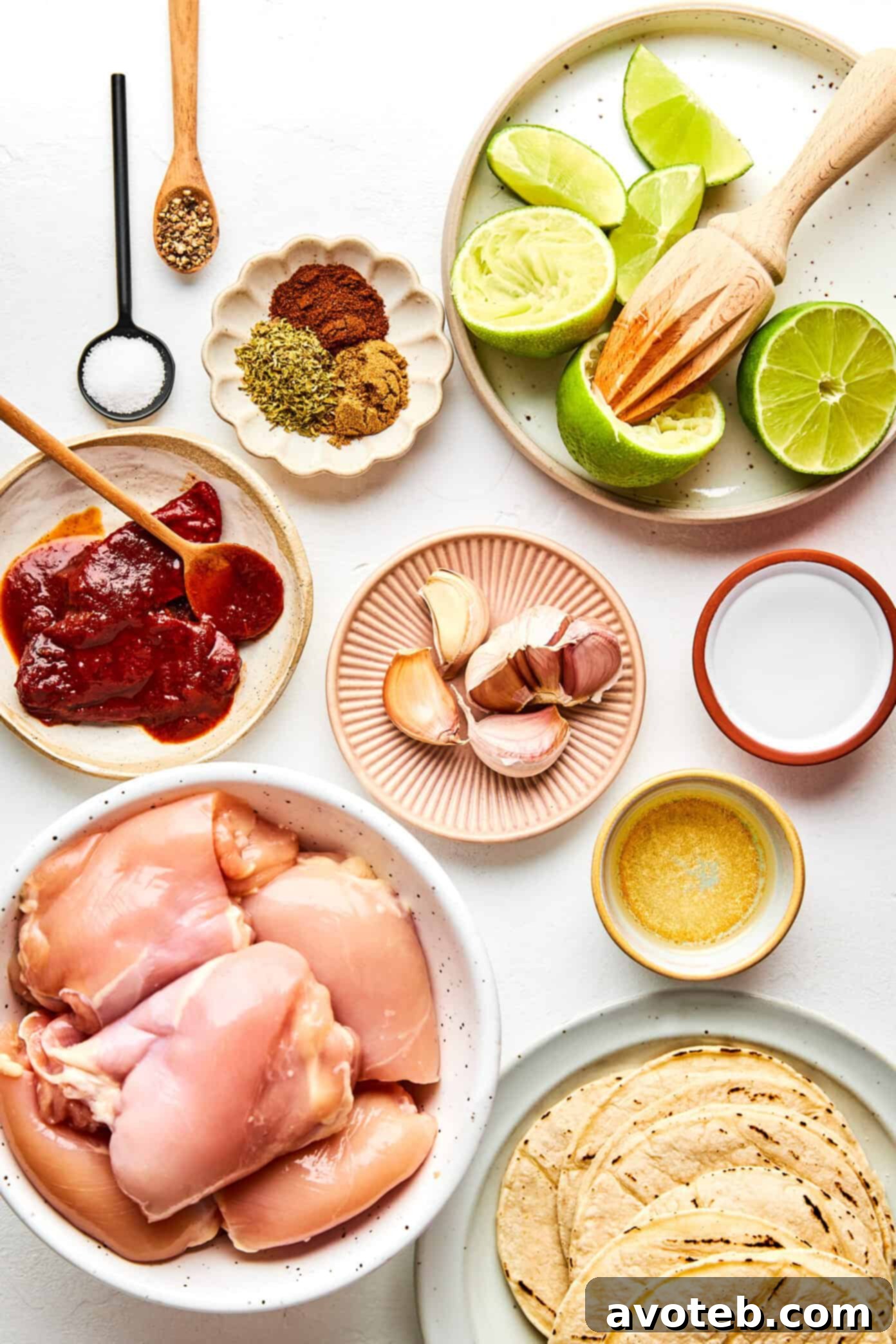 Fresh ingredients laid out on a wooden board, including a blender with marinade, raw chicken thighs, and spices, preparing for the chipotle chicken taco recipe.