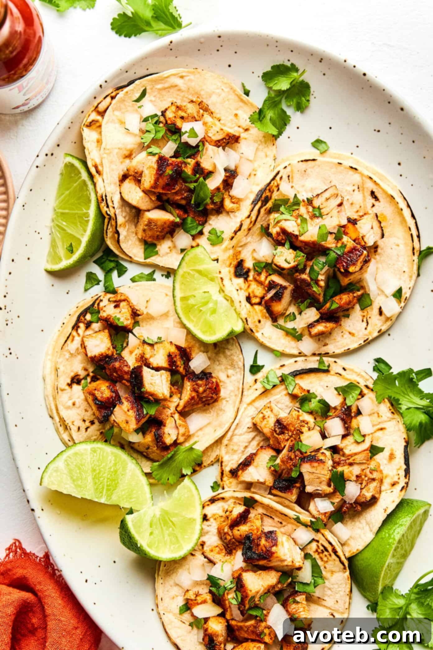 A vibrant close-up of a chipotle chicken taco, garnished with fresh cilantro and onions, ready to be picked up.