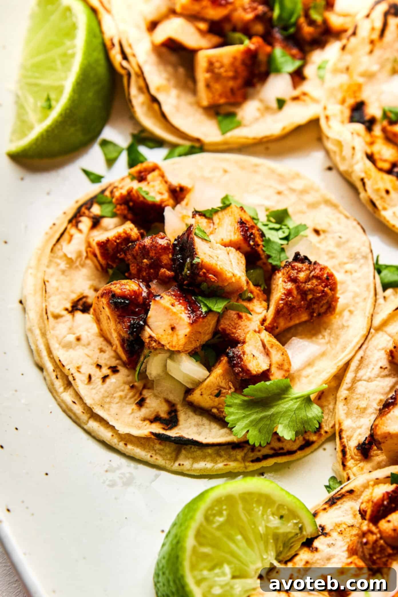 A beautifully presented Chipotle Chicken Taco with various fresh toppings and lime wedges on the side.