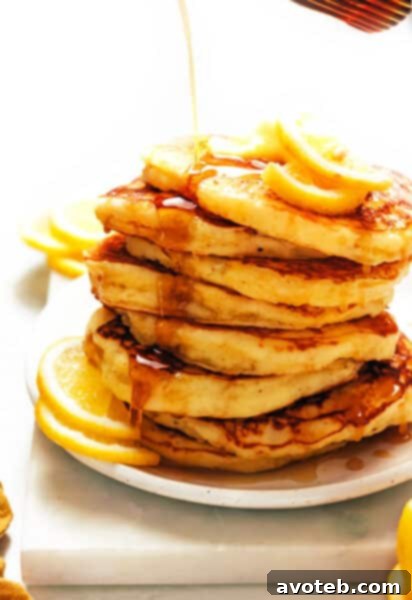 A close-up of a stack of fluffy lemon ricotta pancakes with fresh berries.