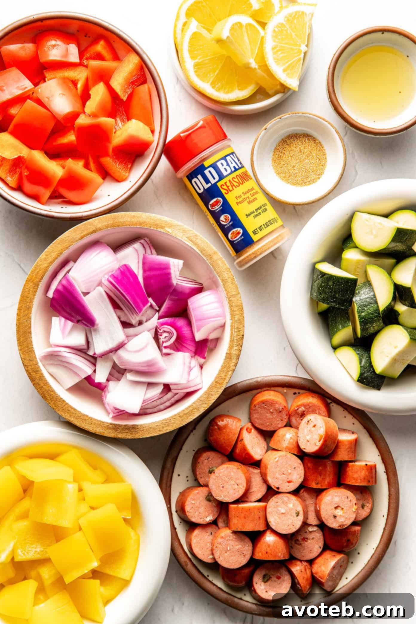 Ingredients for air fryer sausage and veggies laid out, including bell peppers, onion, zucchini, and sausage.