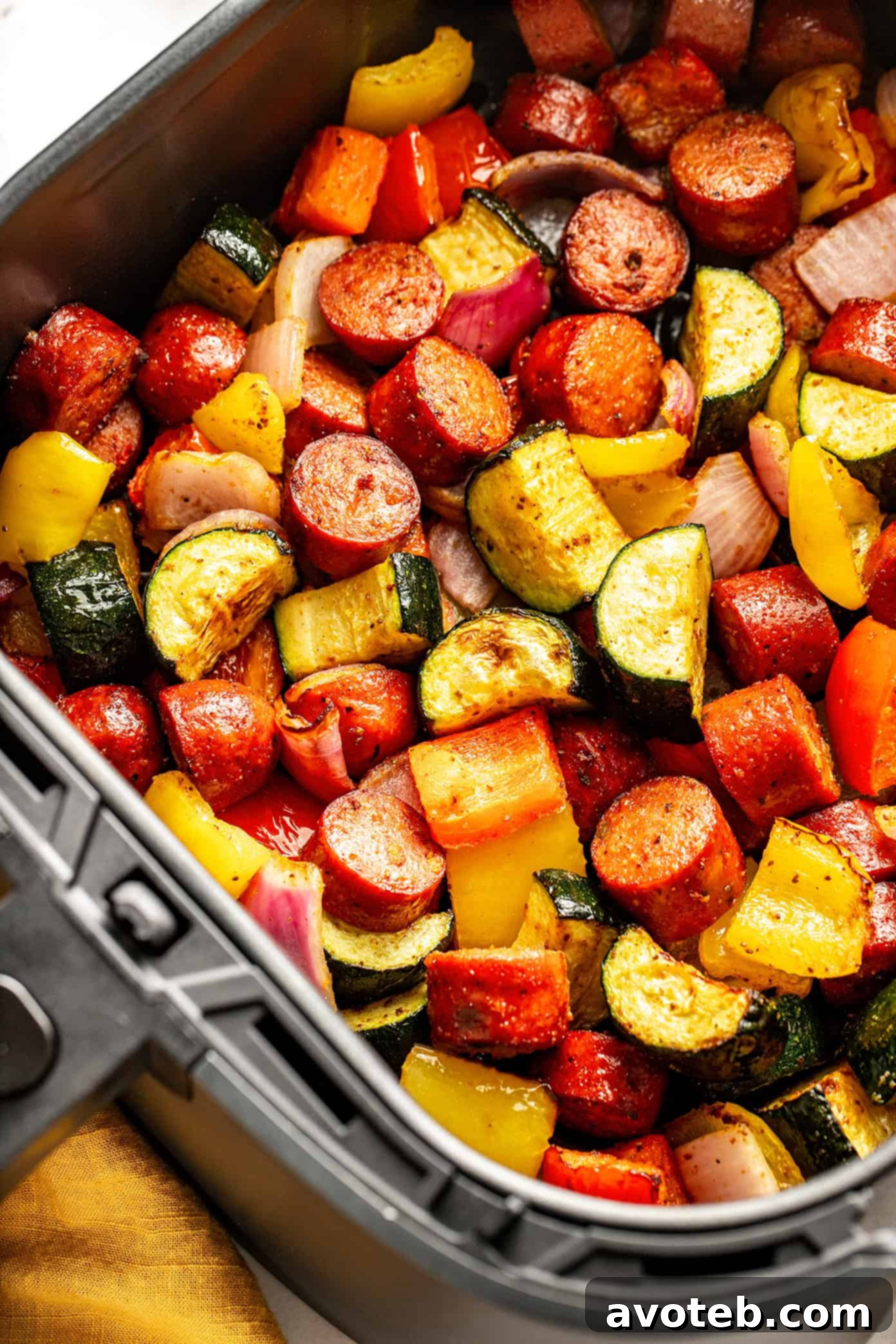 The cooked sausage and veggies being served from the air fryer basket.
